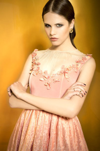 Style #937, knee-length cocktail dress with pleated mesh and flower embroidery around the scoop illusion neckline, jacquard skirt with a bow, available in orange with gold and gray-blue with gold