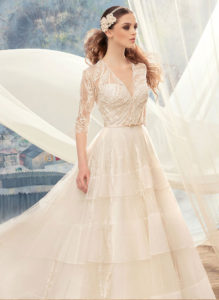 Style #1720L, beaded lace ball gown wedding dress with 3/4 length illusion sleeves and tiered skirt, available in ivory