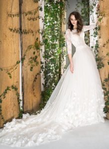 Style #1812Pr, three-quartered sleeve ball gown wedding dress, designed with the illusion neckline, 3-D floral decor, and lace scalloped hem, available in ivory