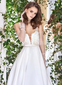 Style #1821L, lace embroidered a-line wedding gown with deep plunging neckline features crisscross spaghetti straps over the low back and satin skirt with pockets, available in ivory