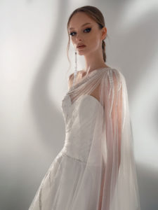 Style #2101, A-line wedding dress with one-shoulder cape sleeve, available in ivory