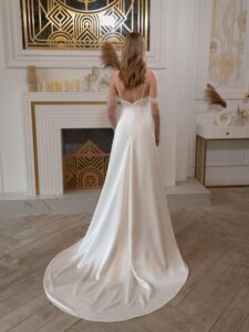 Atlas sheath wedding gown with long off-the-shoulder sleeves; available in ivory-peach