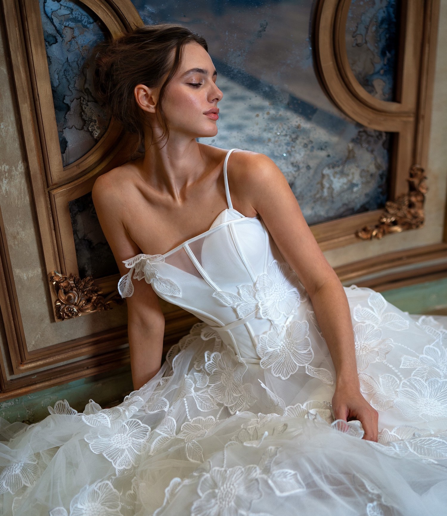 A stunning bride wearing a floral lace wedding gown with a structured bodice and delicate straps, surrounded by an elegant, vintage-inspired backdrop. Perfect for brides searching for Toronto sample sale wedding dresses.