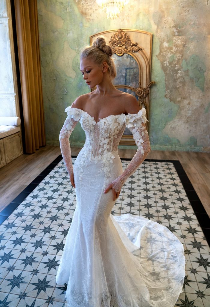 A stunning off-the-shoulder lace wedding gown with floral appliqués, sheer bodice, and a dramatic train. Perfect for an elegant bridal look inspired by Selena Gomez Wedding Dress. Photographed on patterned tiles with a vintage mirror backdrop.