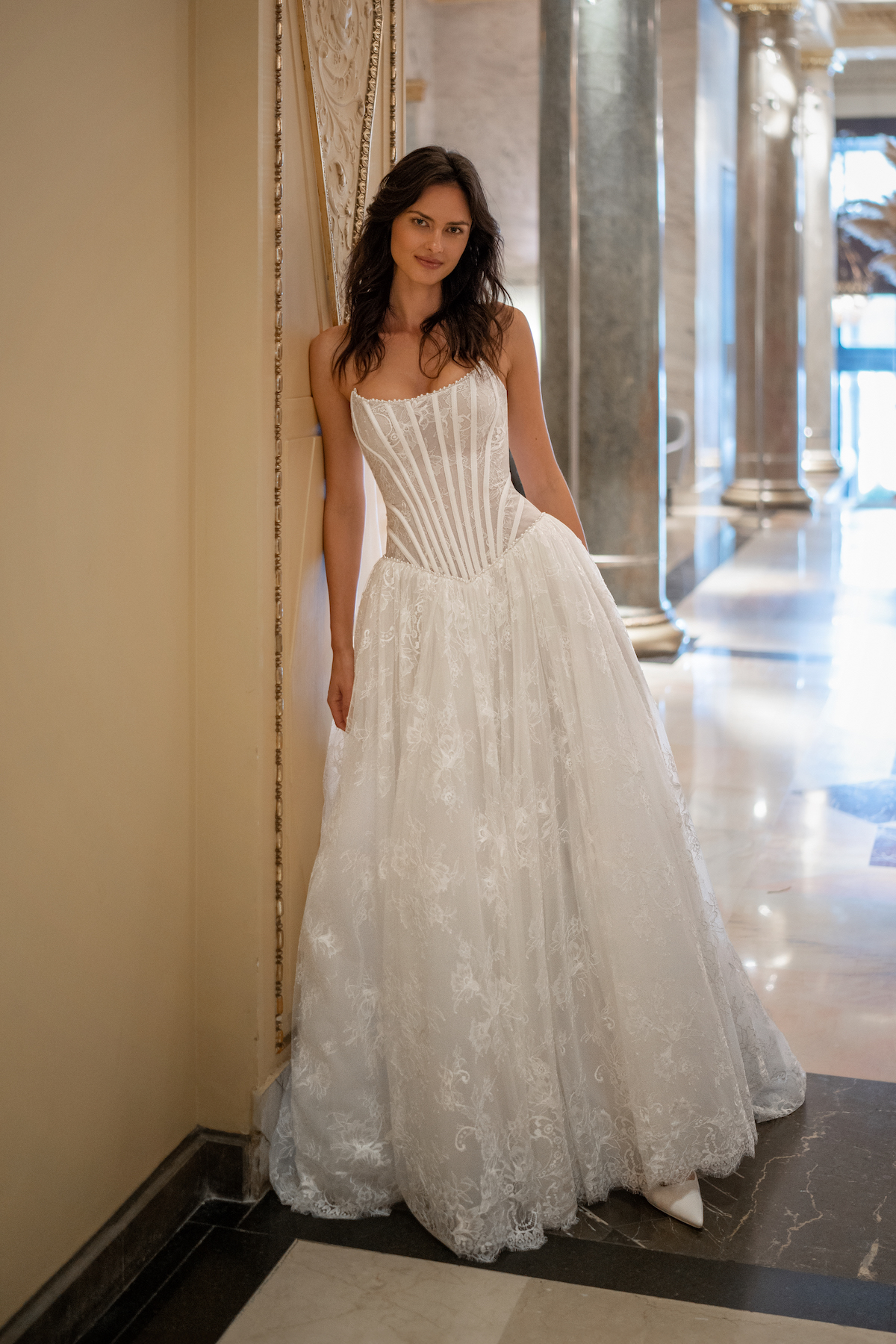 Elegant drop waist wedding dress with a corset-style bodice and intricate lace details, showcased in a grand hall setting at Papilio Boutique in Toronto.