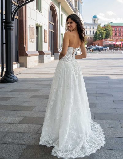 Model in a drop waist wedding dress with modern lace details by Papilio Boutique, posed outdoors on a city street.