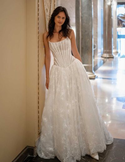 Model dons a modern lace drop waist wedding dress from Papilio Boutique, captured in a lavish corridor.