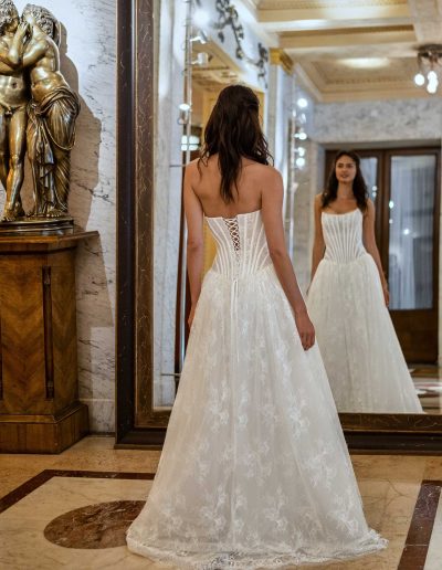 Model wearing a modern lace drop waist wedding gown by Papilio Boutique, showcasing intricate lace back, against an elegant marble interior.