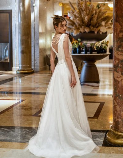 Rear view of a simple wedding gown with pearl back detail, in an ornate hotel setting, from Papilio Boutique Toronto.