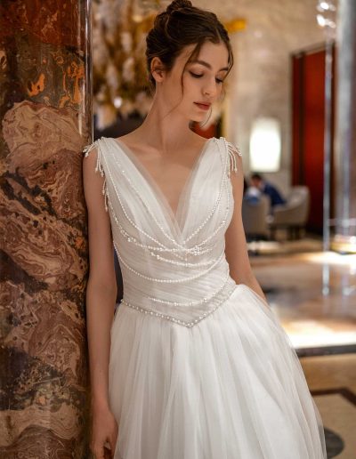 Close-up of a simple wedding dress with pearl details on the bodice, modeled at Papilio Boutique Toronto.