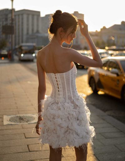 Elegant mini lace wedding dress with exposed corset detailing, sunset city backdrop, from Papilio Boutique bridal store Toronto.