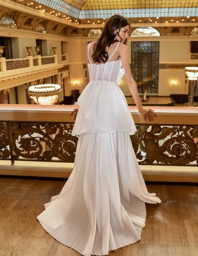 Model displays a convertible wedding dress with elegant ruffles and a long skirt at a luxurious venue, by Papilio Boutique bridal store Toronto.