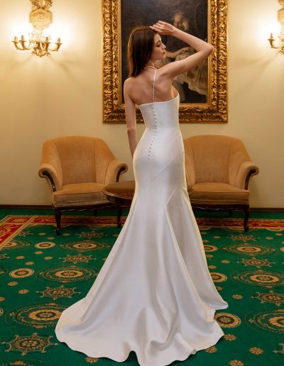 Back view of a simple fitted wedding gown with delicate button details and a train, available at Papilio Boutique Toronto bridal store.