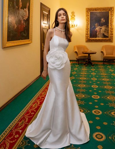 Bride in a fitted wedding gown with a statement flower, seated in a luxurious setting at Papilio Boutique Toronto bridal store.