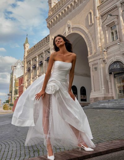 Bride in sexy strapless wedding dress with open leg on city street, by Papilio Boutique Toronto bridal store.