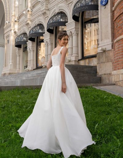 Back view of a bride in a basque waist wedding dress, showcasing detailed lace and a flowing skirt, by Papilio Boutique Toronto bridal store.