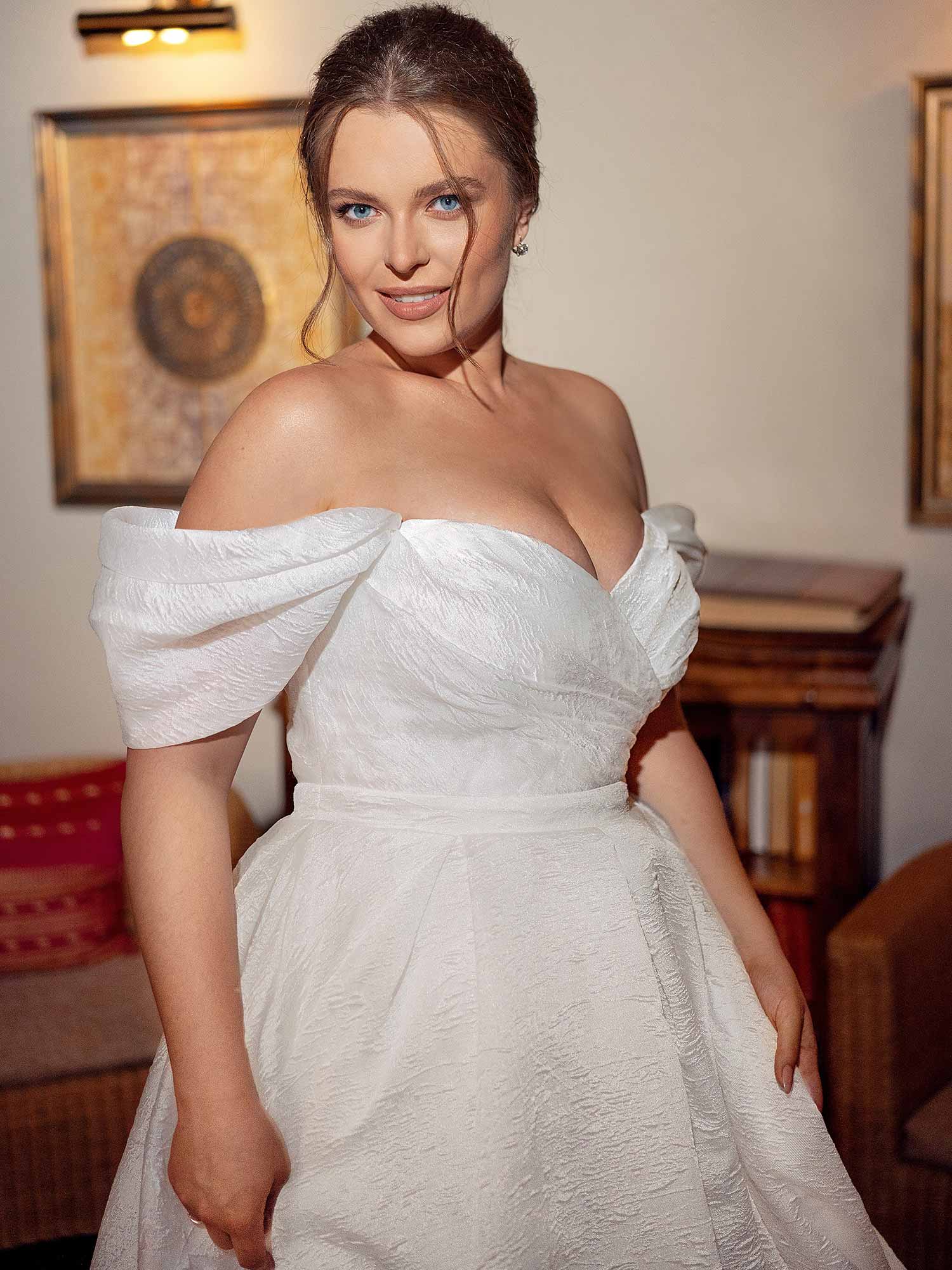 Best Wedding Dress for Body Type - Full Chested: Elegant off-the-shoulder A-line wedding dress with a structured bodice and draped neckline, designed to provide support and enhance a full bust. Available at Papilio Boutique in Toronto.