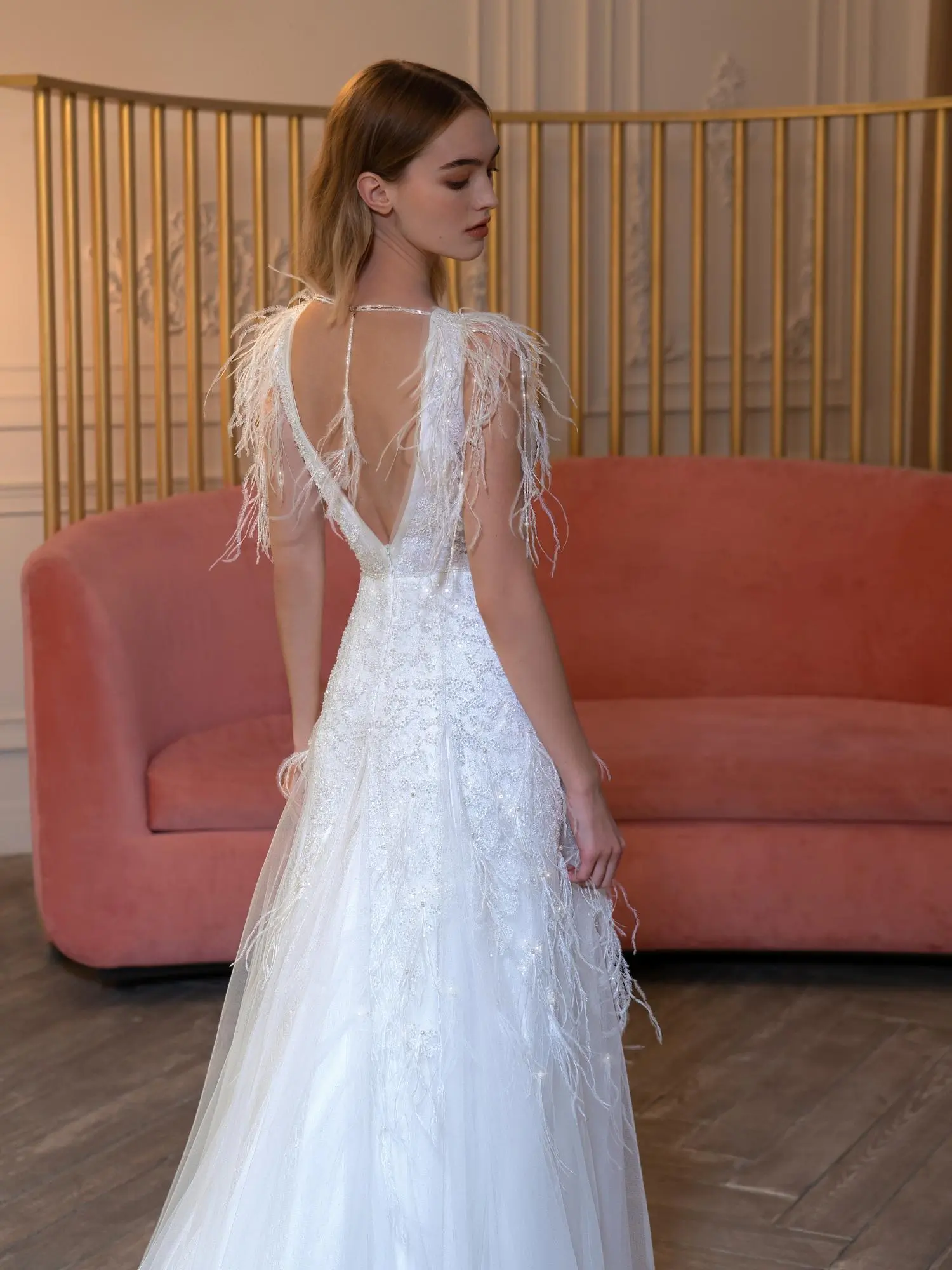 Elegant sheath wedding dress with a plunging V-back, feathered shoulder details, and subtle beading, designed to enhance petite body types. Find the Best Wedding Dress for Body Type at Papilio Boutique in Toronto.